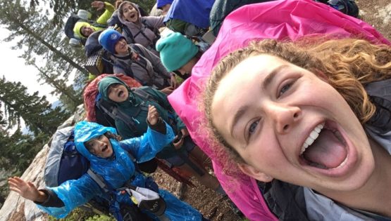 Teens taking a group selfie with backpacks on at the Women of the Wild quest
